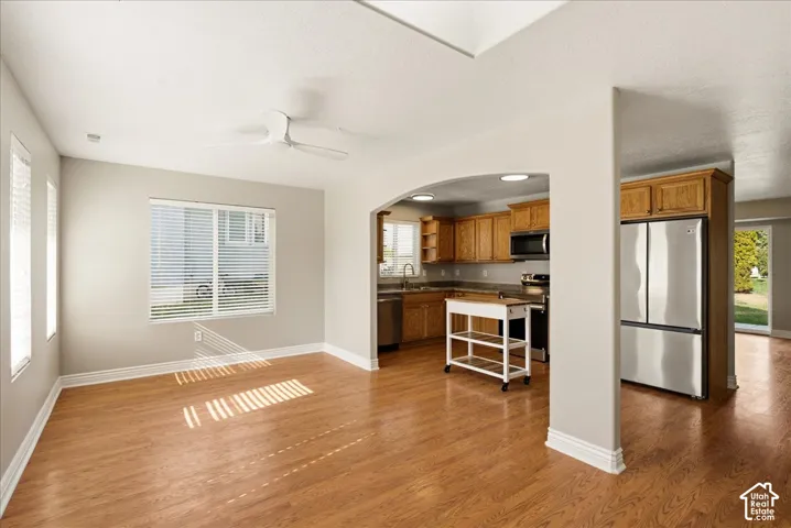 Wood-finish flooring, arched entryway, ceiling fan, and stainless steel refrigerator