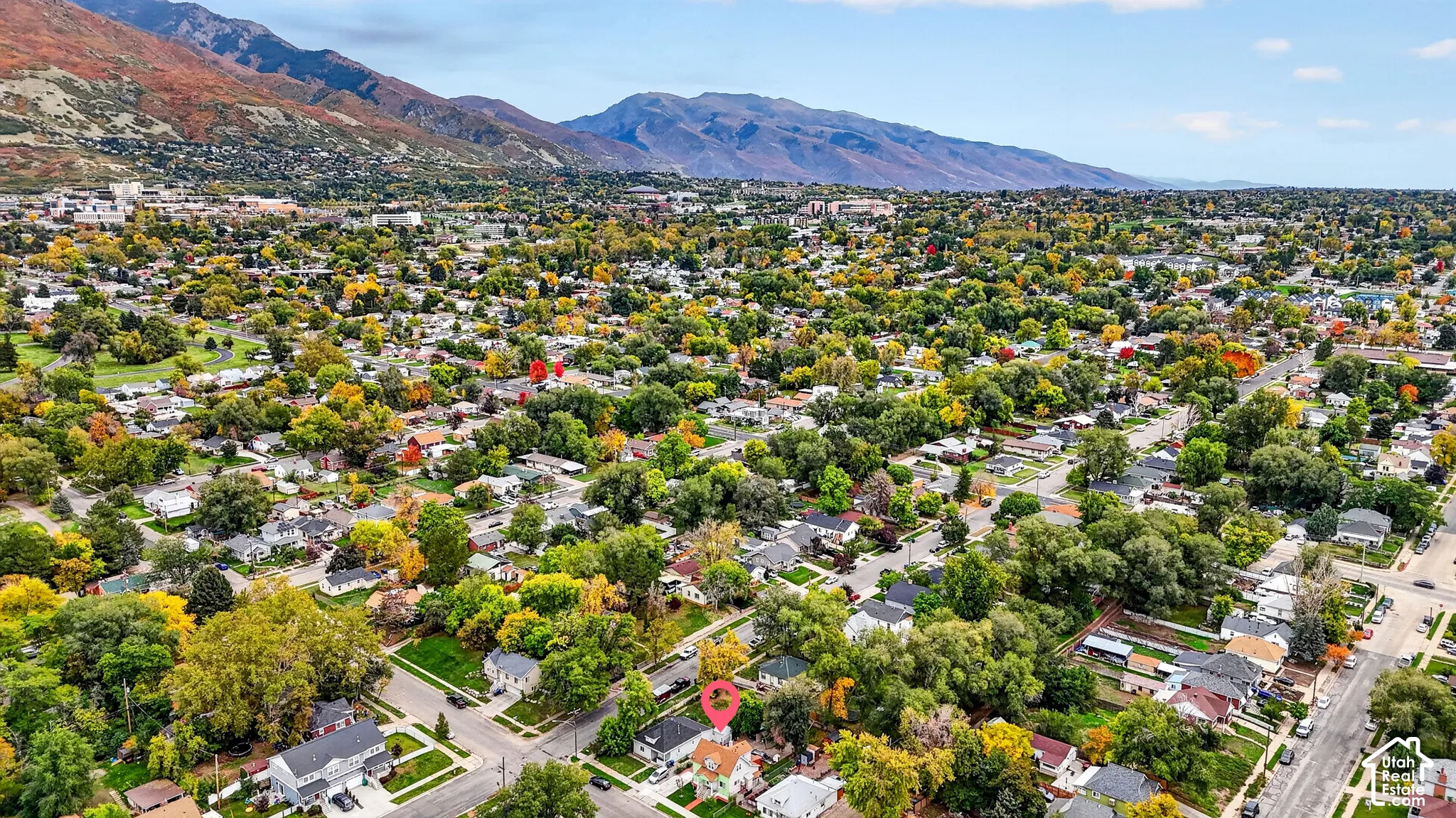 Aerial perspective of a corner lot property featuring mature trees and mountain scenery