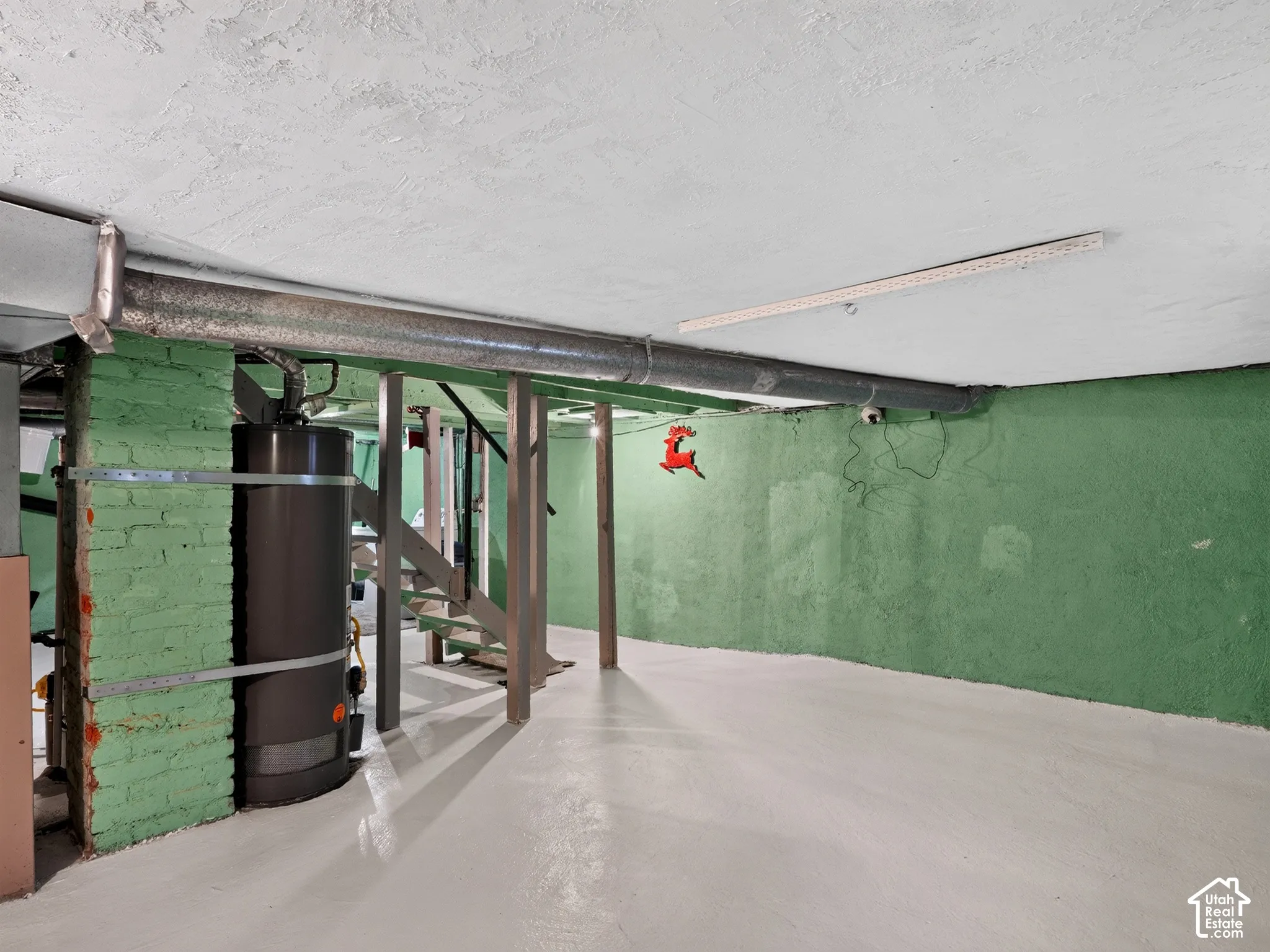 Basement - Unfinished lower level featuring painted masonry walls, exposed ceiling joists, painted concrete flooring, and structural support posts