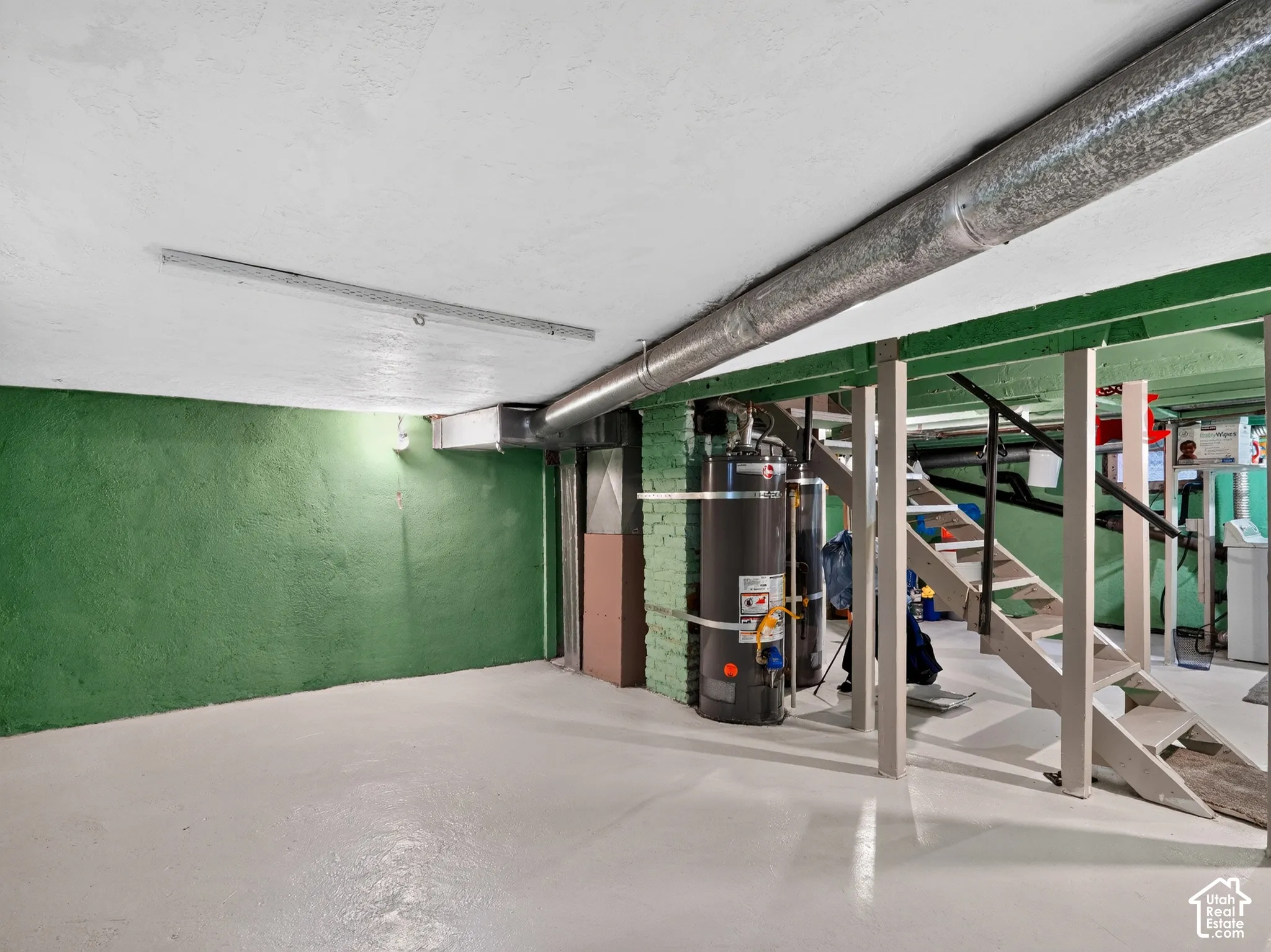 Basement - Unfinished lower-level space featuring painted concrete walls, painted concrete flooring, exposed structural support posts, a staircase, and 2 new water heaters