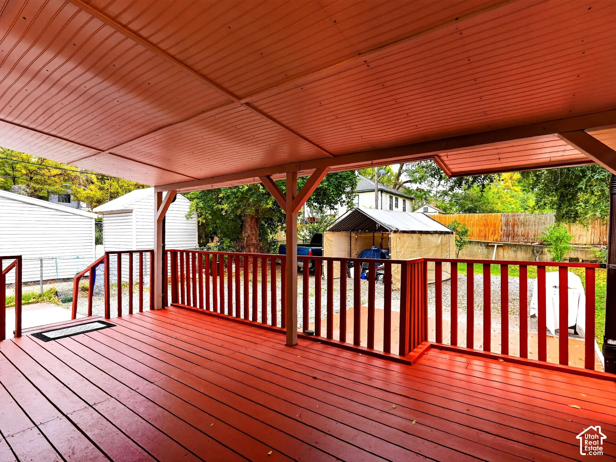 Covered wooden deck featuring a solid-color finish and perimeter railings