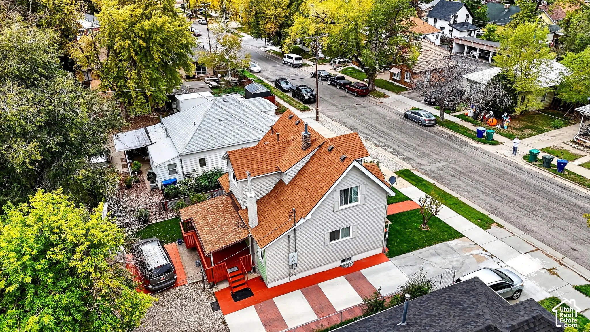 Multi-story residence with light-colored siding, textured shingle roof, concrete driveway, and gated side yard