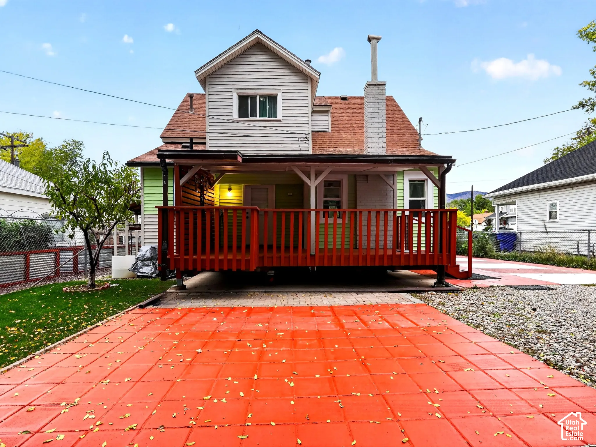 Exterior featuring a raised wood deck, masonry chimney, siding, and paver patio
