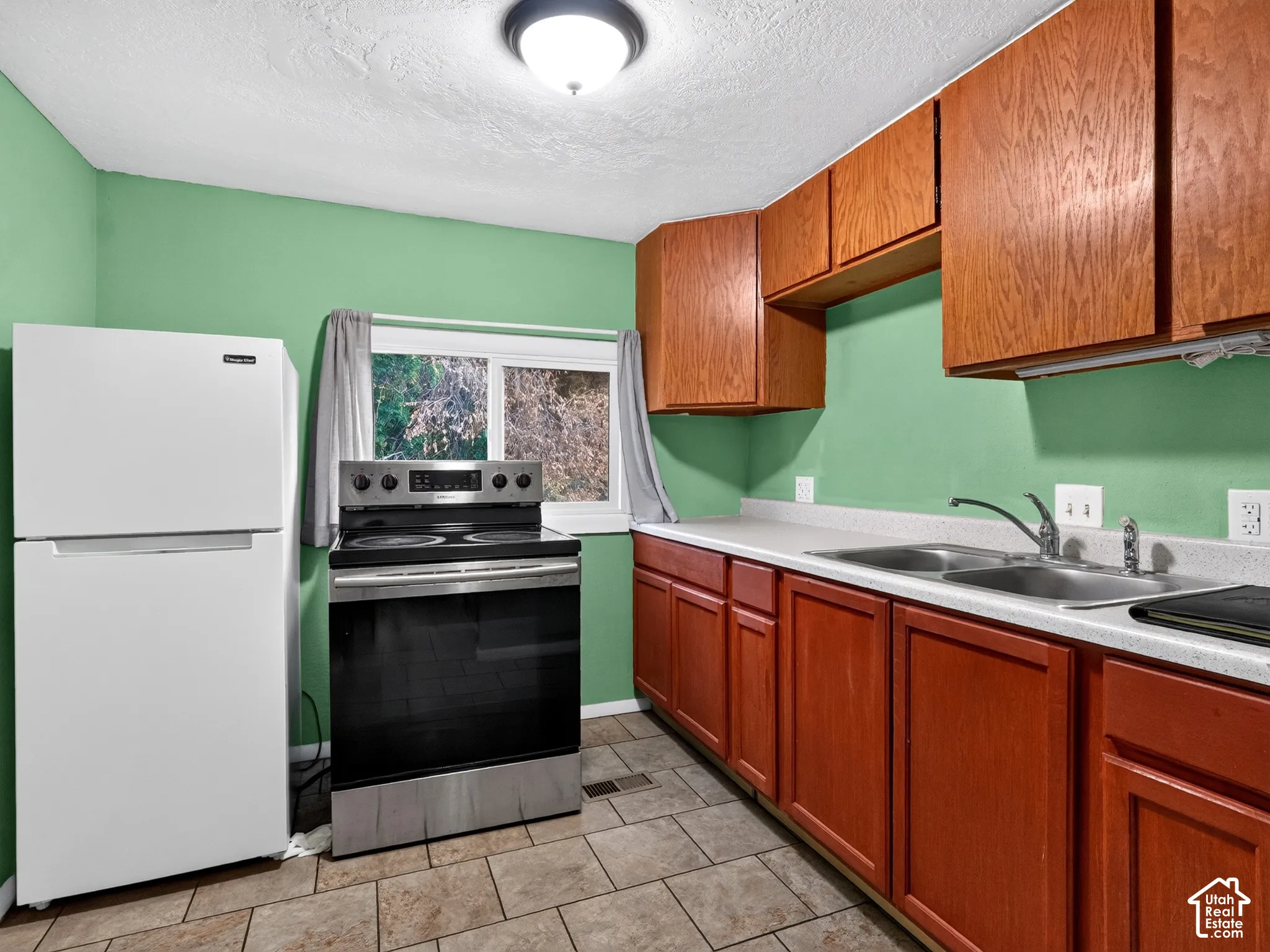 1 bedroom unit - Kitchen featuring wood cabinetry, stainless steel electric range, white refrigerator, solid surface countertops with a dual-basin sink, and tile flooring