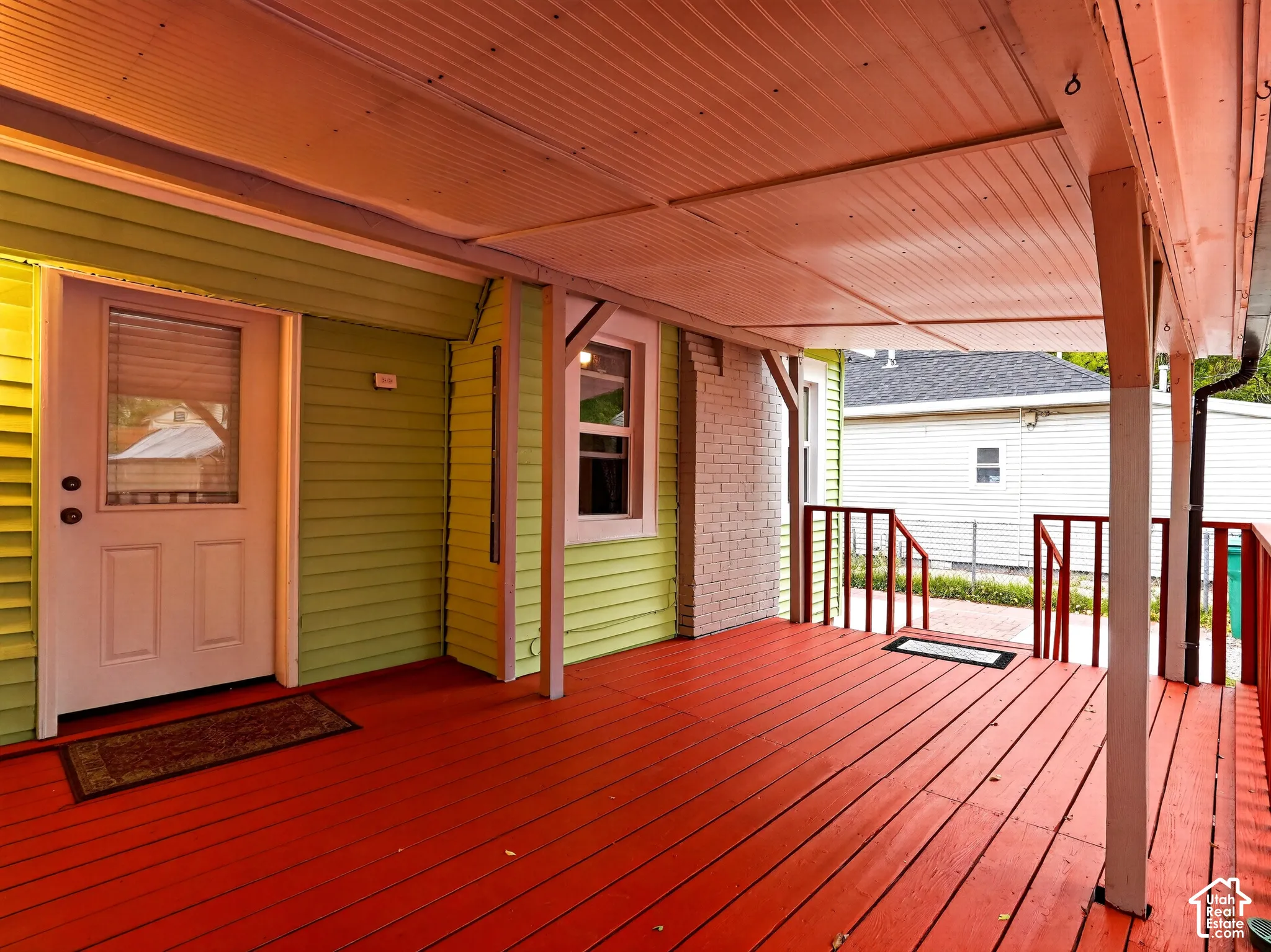 Covered porch with painted wood decking, horizontal lap siding, brick chimney exterior, and simple post-and-beam supports