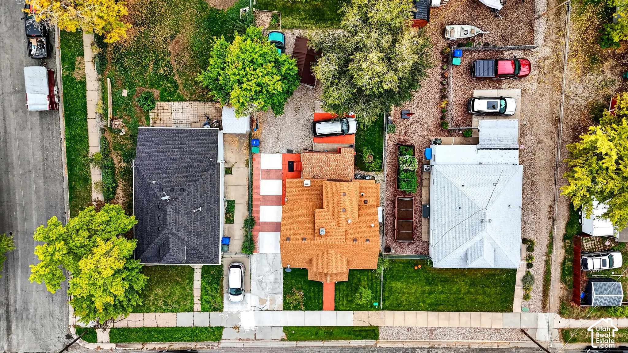 Aerial perspective of the property featuring a detached garage, concrete driveway, stone-surfaced parking area, and manicured rear lawn
