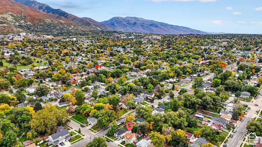 Aerial perspective of a corner lot property featuring mature trees and mountain scenery