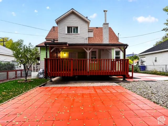 Exterior featuring a raised wood deck, masonry chimney, siding, and paver patio