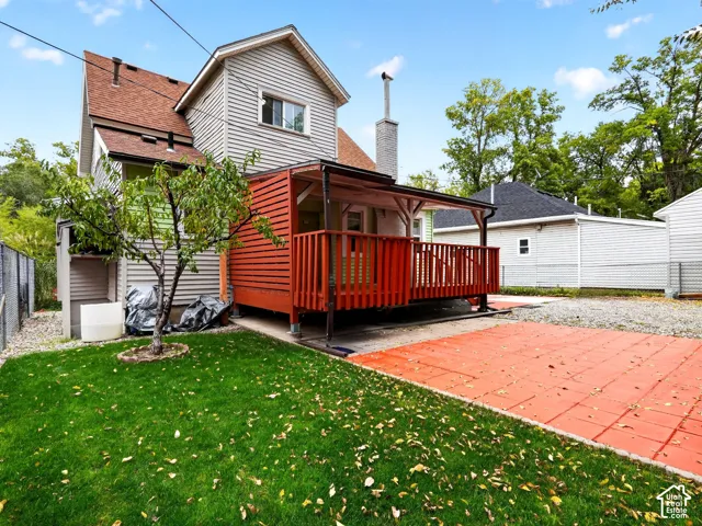 Exterior featuring a covered wood deck, red paver patio, siding facade, and mature landscaping