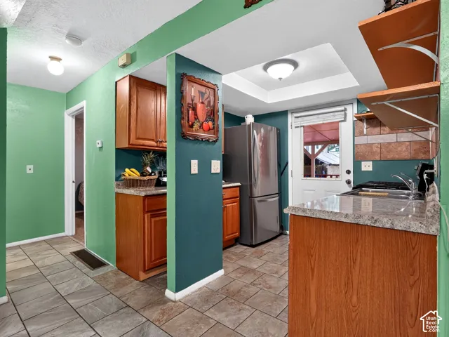 2 bedroom unit - Kitchen featuring wood cabinetry, stone-finish countertops, stainless steel refrigerator, recessed lighting, and tile flooring
