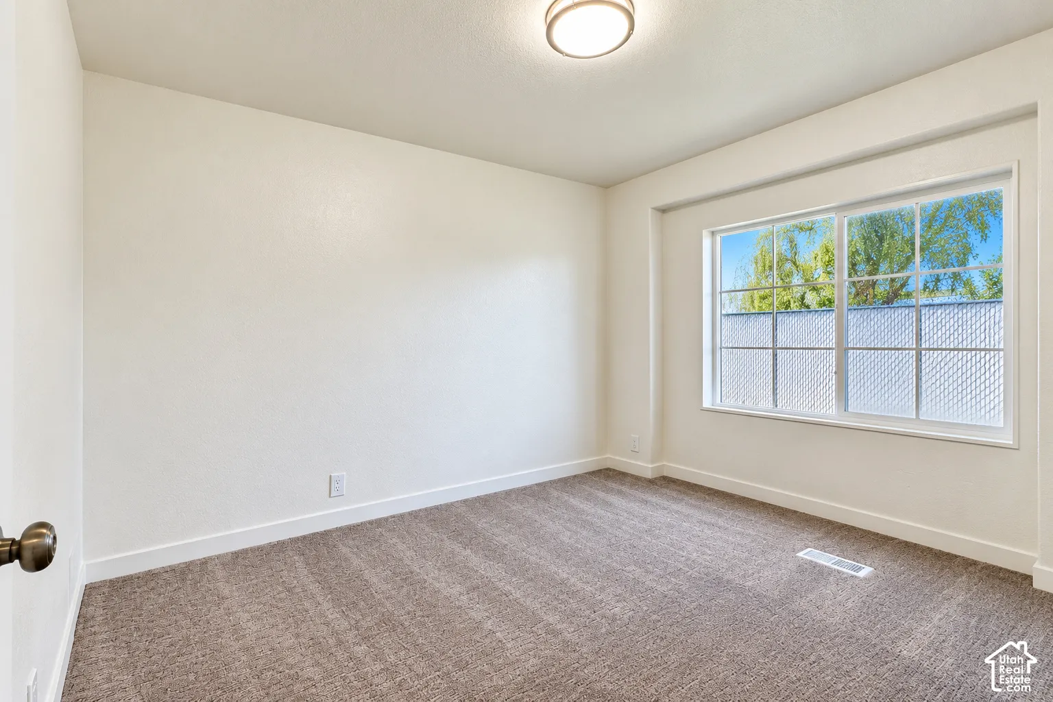Room featuring neutral wall tones, wall-to-wall carpeting, a multi-pane window with grid detailing, and a flush-mount ceiling fixture
