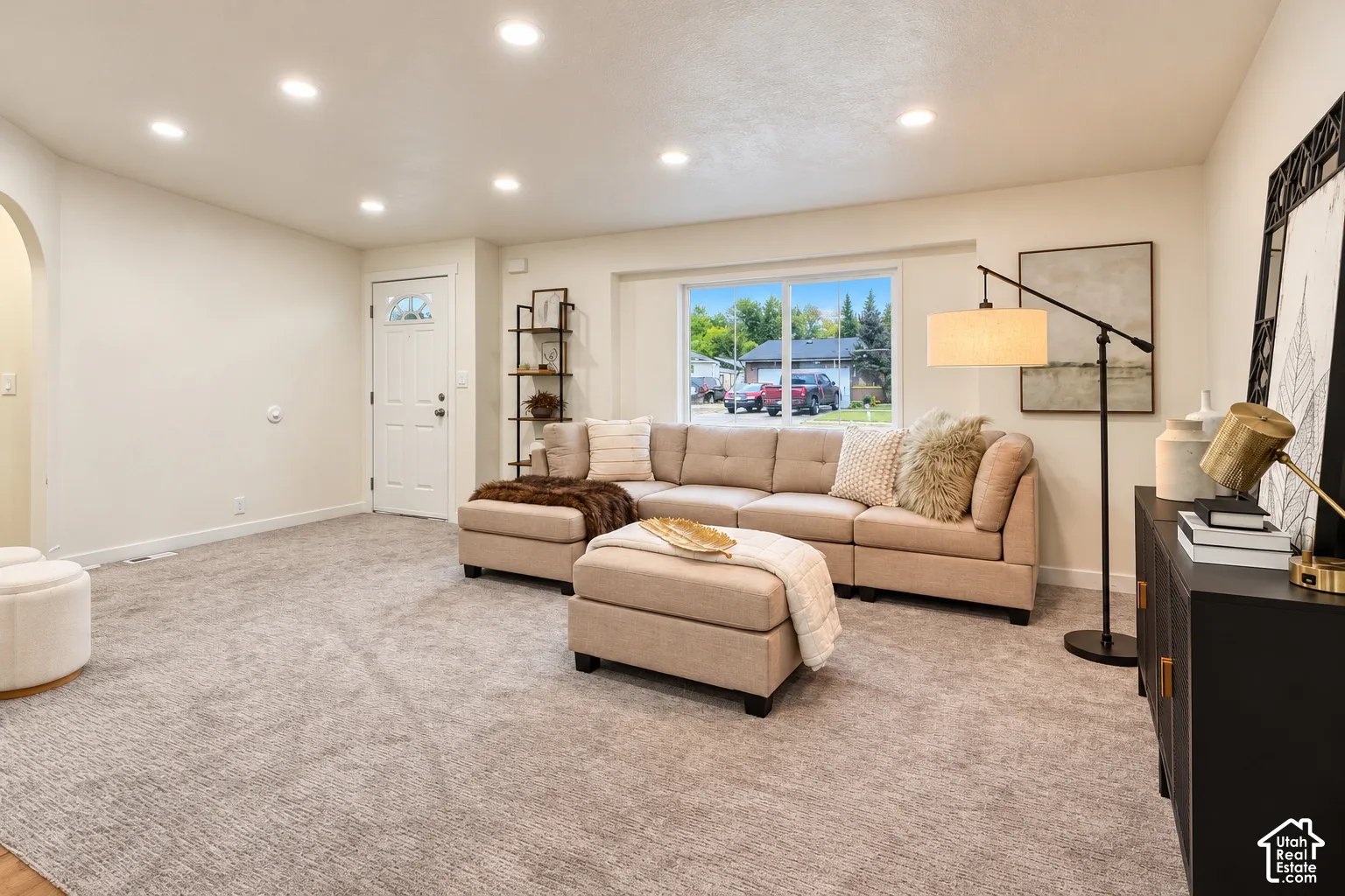 Neutral-toned interior space featuring recessed ceiling lighting, wall-to-wall carpeting, an arched entryway, and a picture window