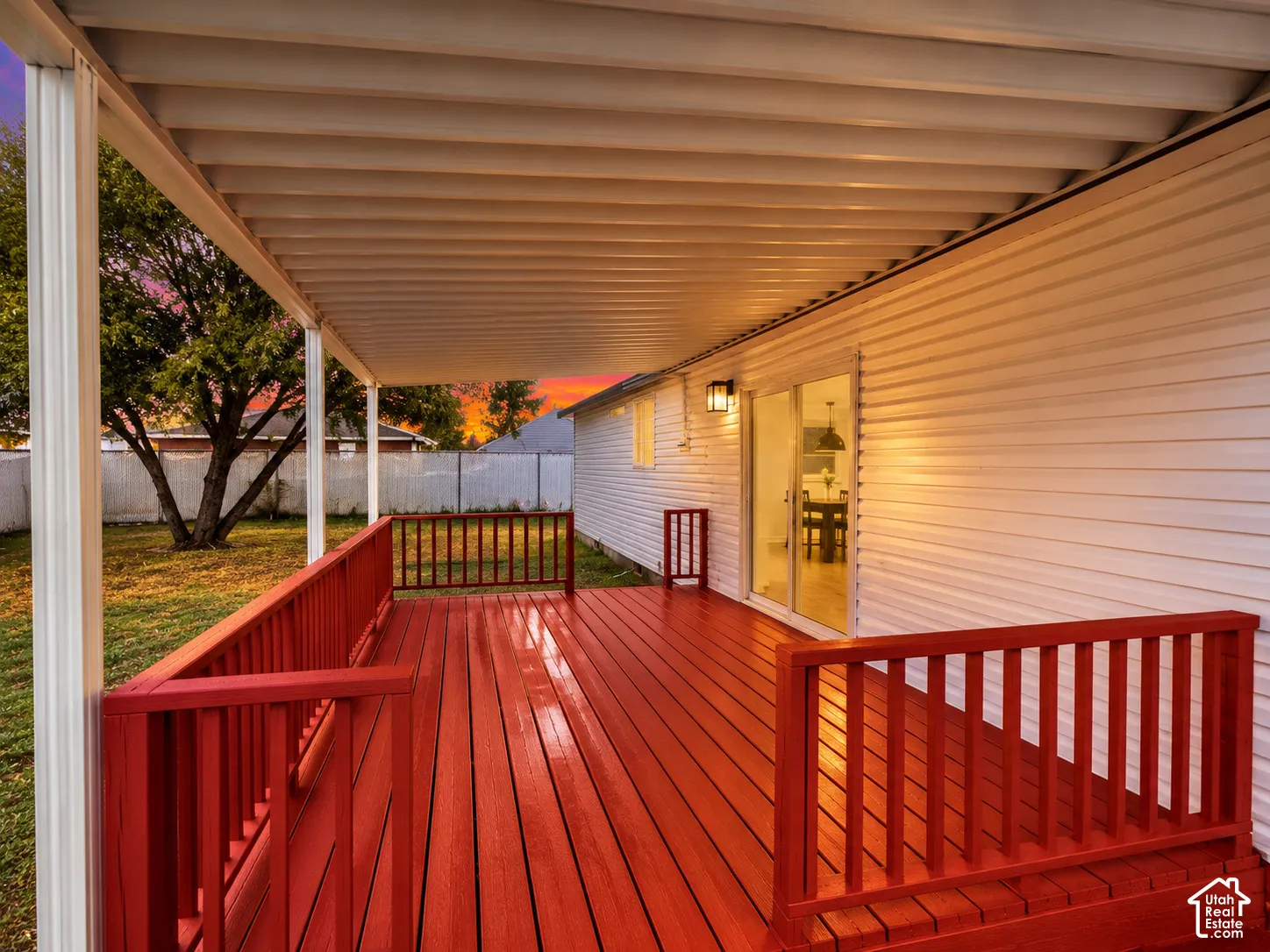 Covered deck featuring wood-finish decking, painted wooden railings, and sliding glass exterior doors