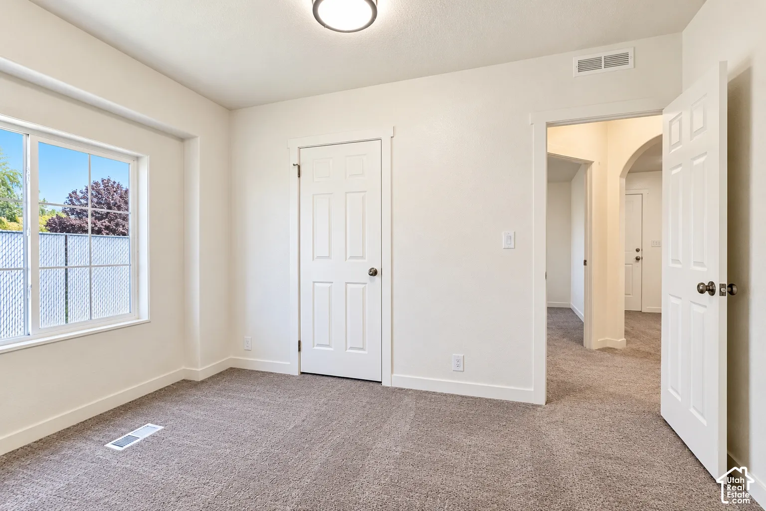 Neutral-toned wall-to-wall carpeting, six-panel interior doors, multi-lite window, and arched entryways