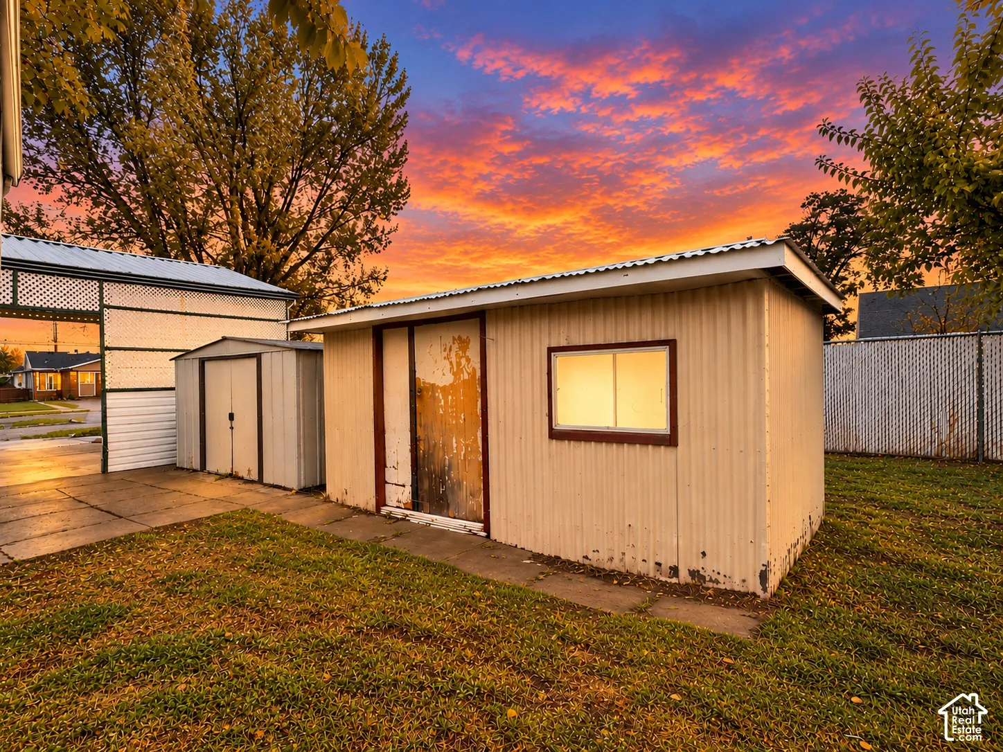 Exterior storage structures featuring corrugated metal siding, concrete pad foundations, and chain-link perimeter fencing