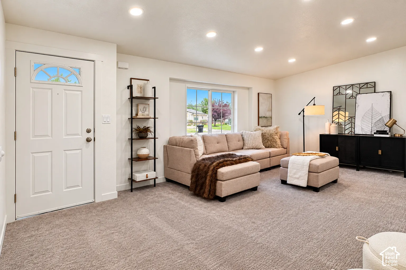 Neutral wall-to-wall carpeting, recessed ceiling lighting, and a single-panel entry door featuring an arched window insert with decorative muntins
