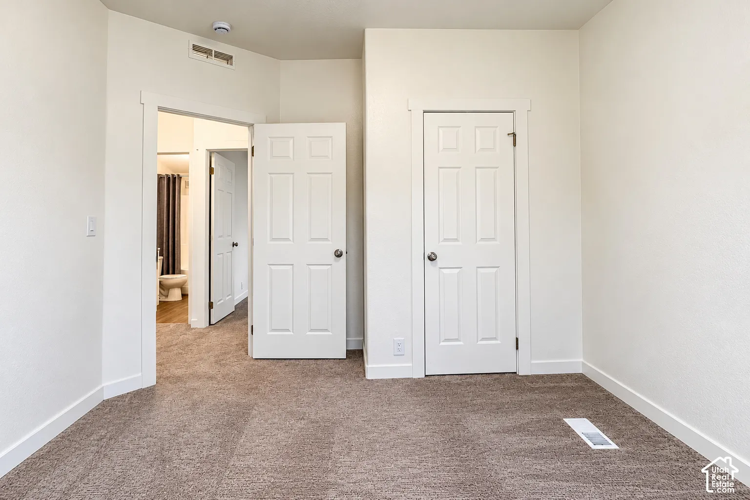Interior room featuring neutral-toned carpeting, two-panel interior doors, and white-painted trim