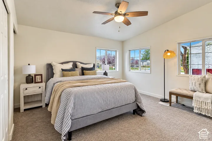 Neutral-toned interior space featuring vaulted ceilings, multi-pane windows, and a ceiling fan with integrated lighting