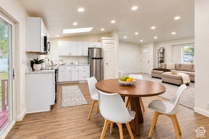 Kitchen featuring white cabinetry, stone-finish countertops, stainless steel appliances, recessed lighting, and a ceiling skylight