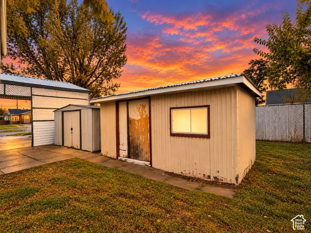 Exterior storage structures featuring corrugated metal siding, concrete pad foundations, and chain-link perimeter fencing