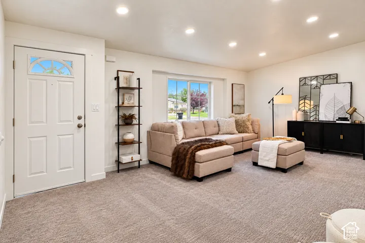 Neutral wall-to-wall carpeting, recessed ceiling lighting, and a single-panel entry door featuring an arched window insert with decorative muntins