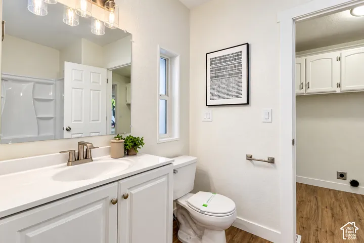 Bathroom featuring a white vanity with an integrated sink, brushed-nickel faucet, large frameless mirror, vanity lighting, and a composite tub-and-shower surround