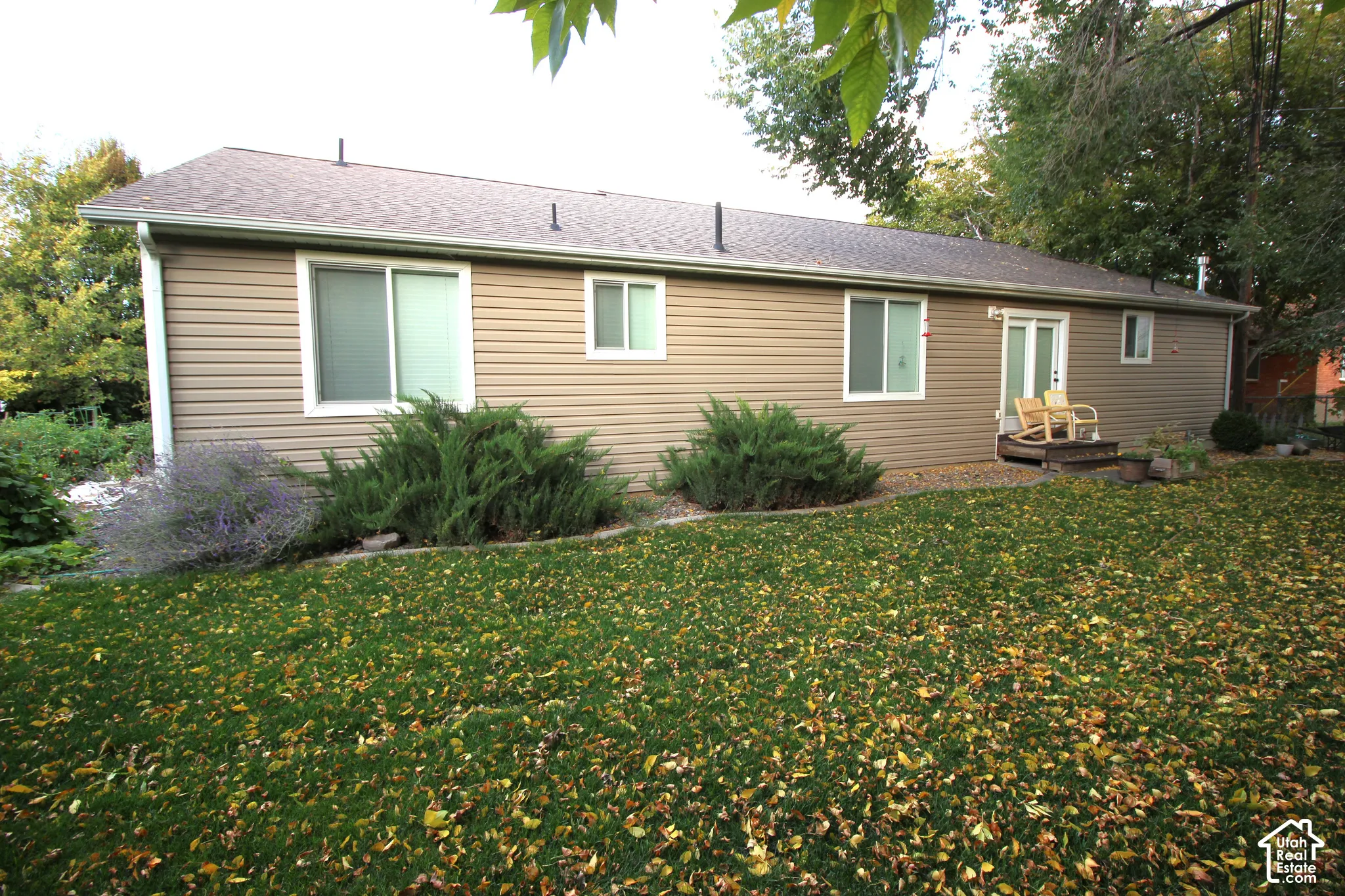 Exterior features include horizontal vinyl siding, a composition shingle roof, sliding glass doors, and mature landscaping