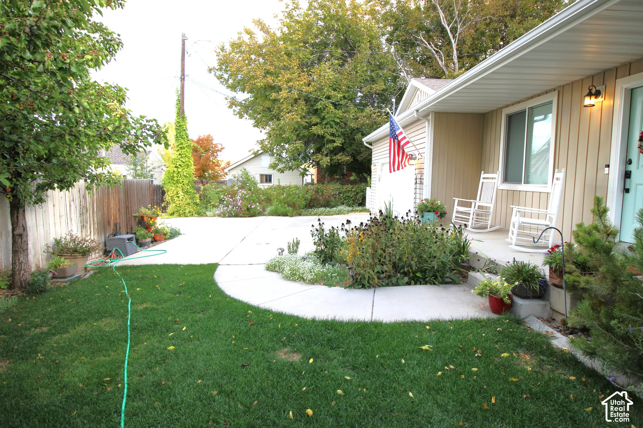 Exterior featuring vertical siding, concrete patio, landscaped garden beds, and wood-panel fencing
