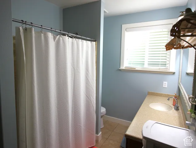 Master Bathroom featuring a solid-surface countertop with an integrated oval sink, ceramic tile flooring, and a window with horizontal blinds