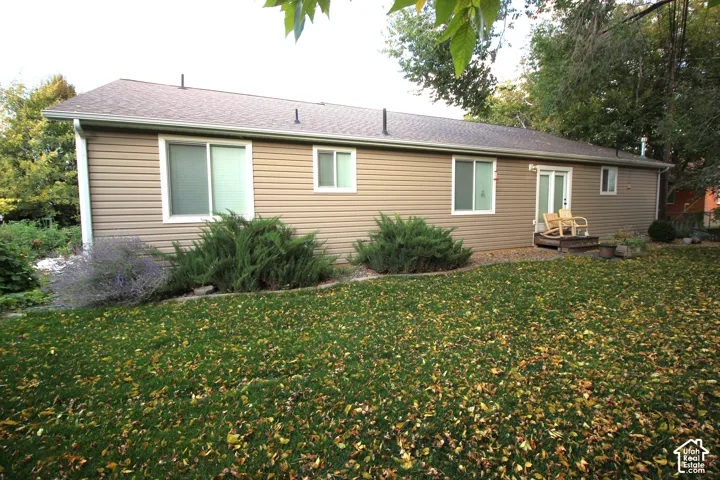 Exterior features include horizontal vinyl siding, a composition shingle roof, sliding glass doors, and mature landscaping