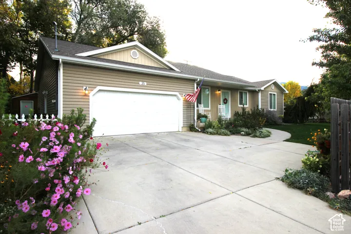 Single-story residence featuring horizontal vinyl siding, a two-car garage, concrete driveway, and landscaped garden beds