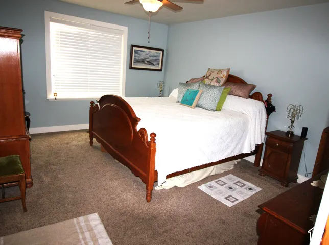 Master Bedroom featuring wall-to-wall carpeting, a multi-pane window with blinds, and a ceiling fan