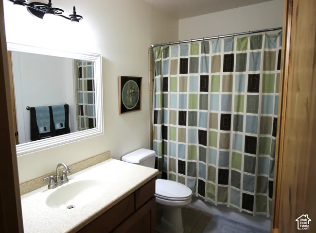 2nd Bathroom featuring a wood-finish vanity, solid-surface countertop with an integrated oval sink, framed wall mirror, and a three-light fixture