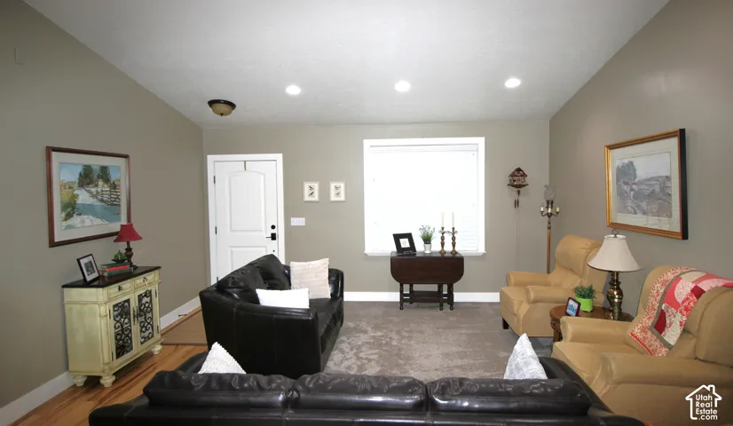Living area featuring vaulted ceilings, recessed lighting, neutral wall paint, and Hickory hardwood flooring