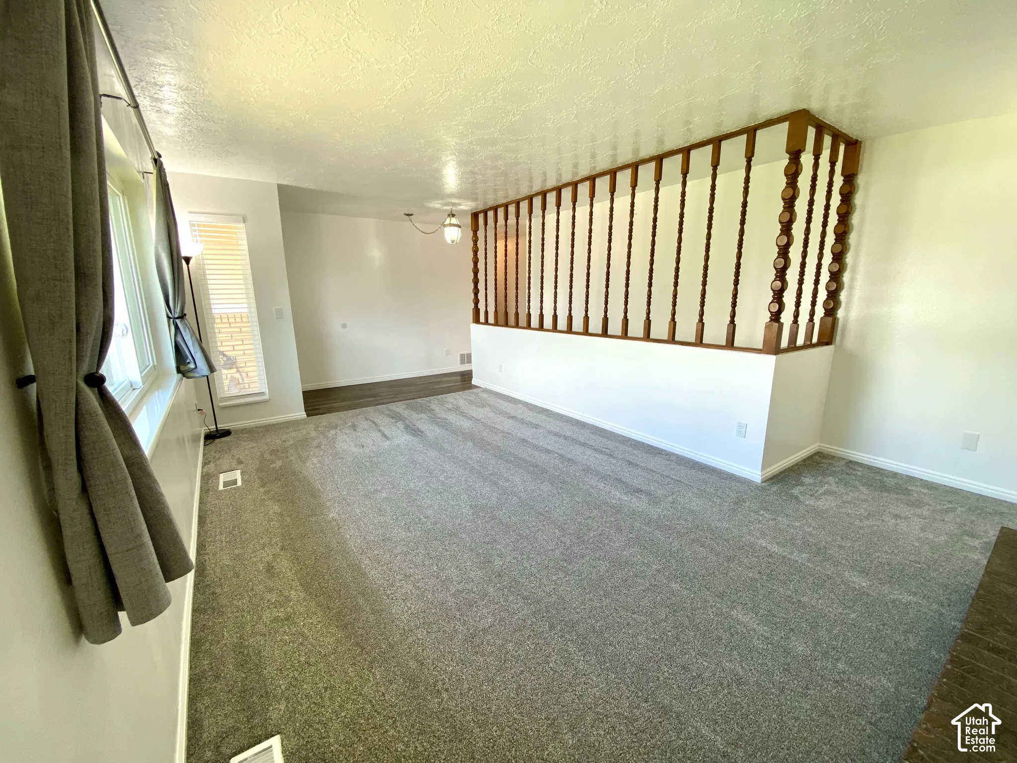 Neutral-toned wall-to-wall carpeting, decorative wood-spindle room divider, and flush-mount ceiling light fixture