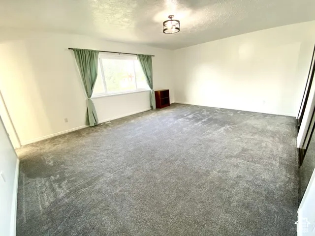 Interior room featuring wall-to-wall carpeting, neutral wall coloring, a large picture window, and a drum-style ceiling light fixture