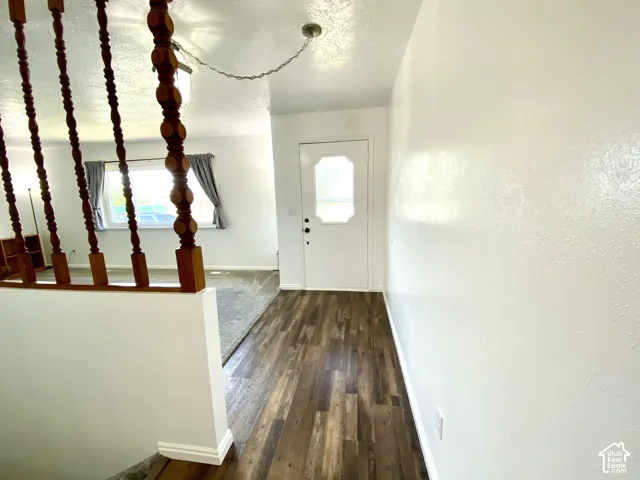 Entryway featuring wood-finish flooring, a white paneled door with an inset window, and wood-turned spindle balusters