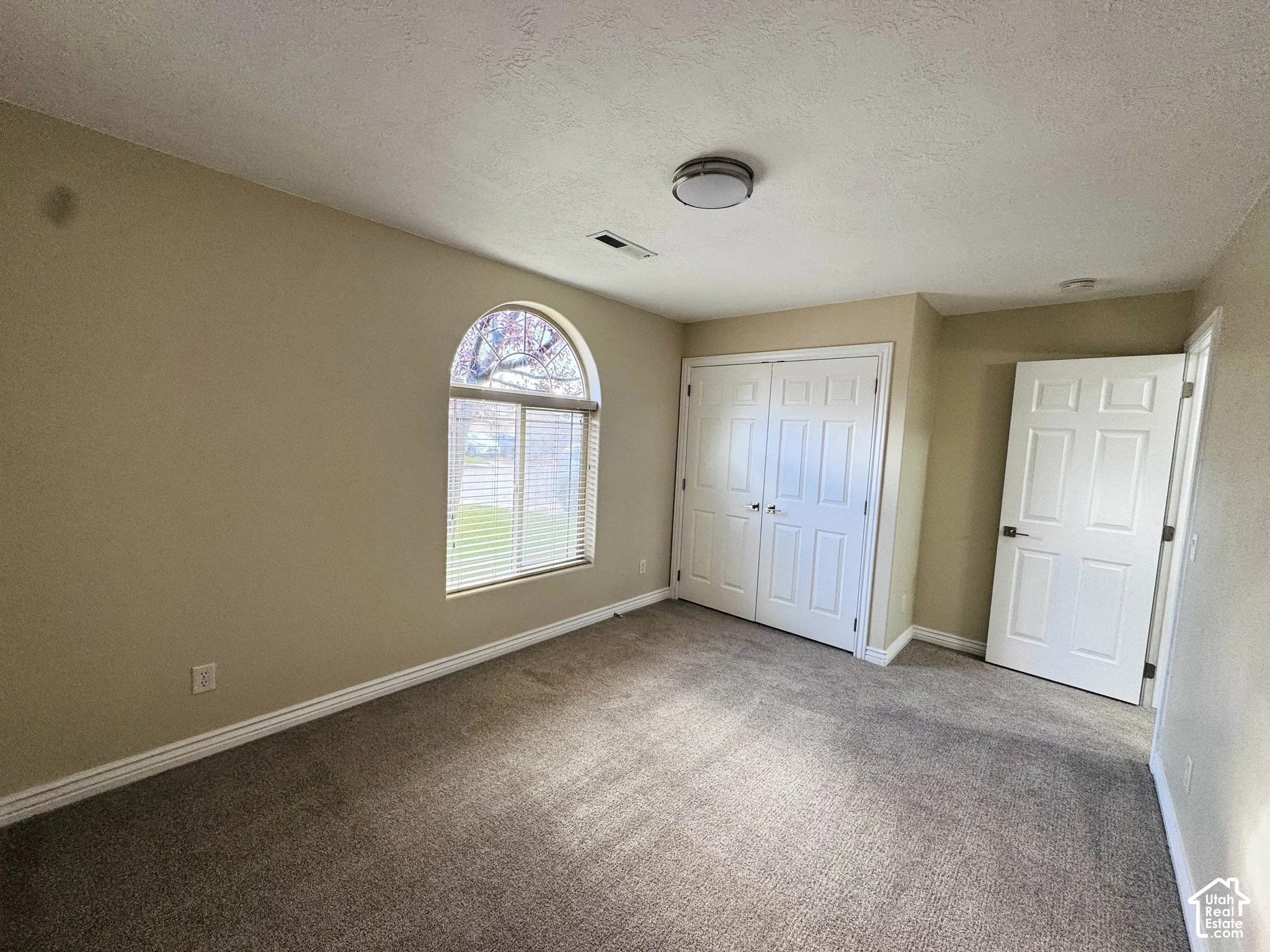 Arched window with decorative transom, wall-to-wall carpeting, double-door closet, and interior paneled door
