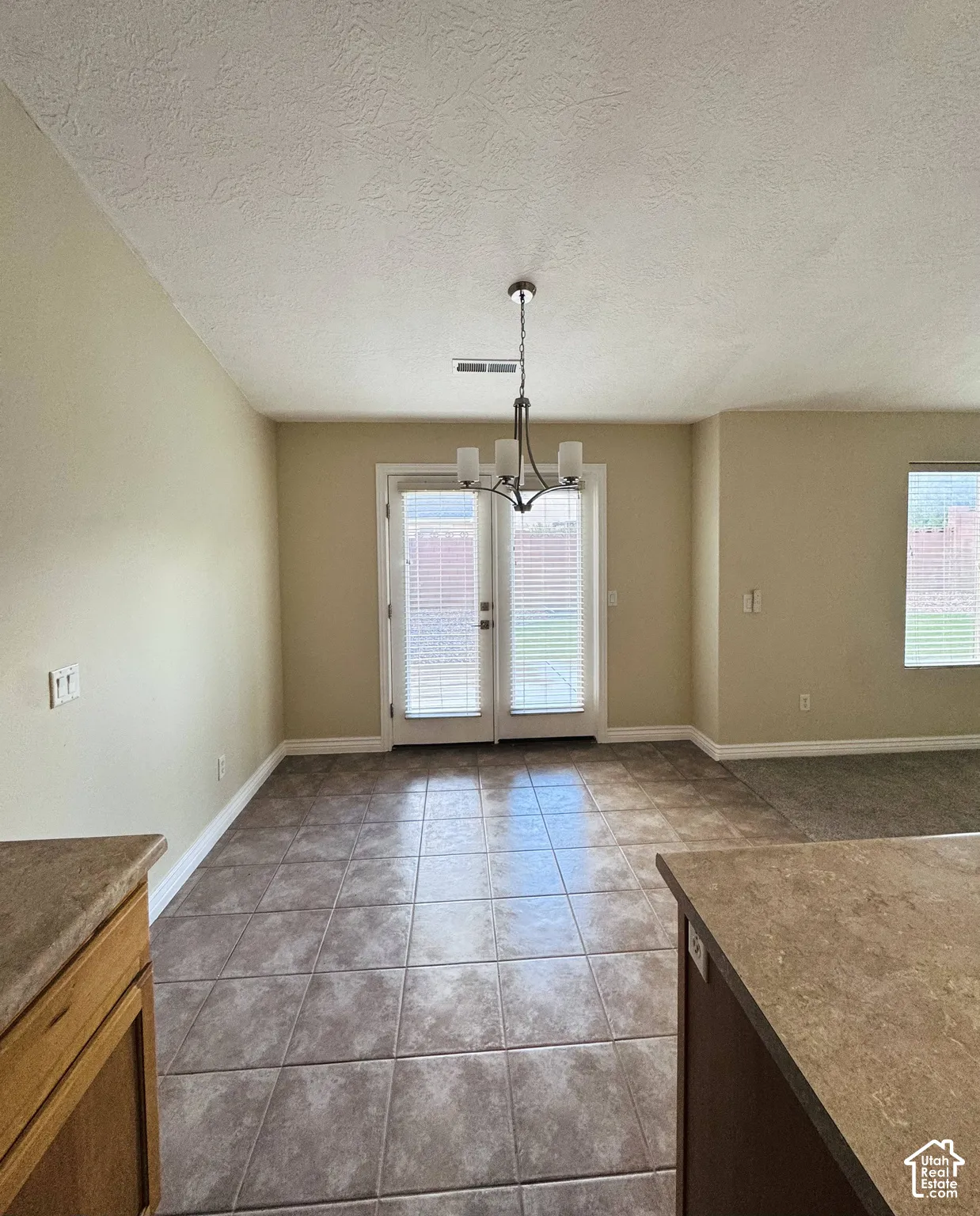 Ceramic tile flooring, glass-paned double doors, multi-arm metal chandelier, and vaulted ceiling