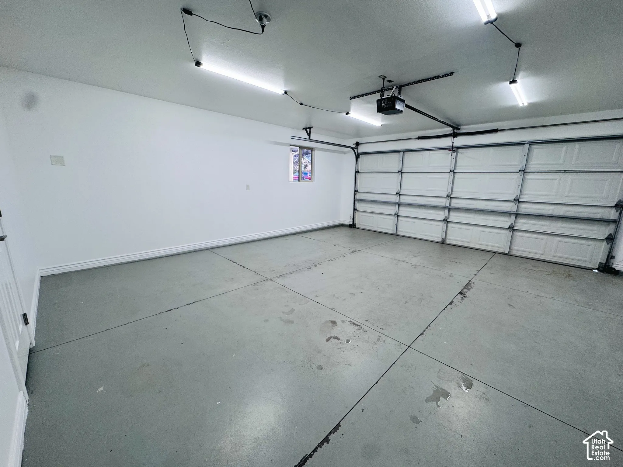 Multi-car garage featuring a sectional overhead door, painted concrete flooring, linear lighting, and a window