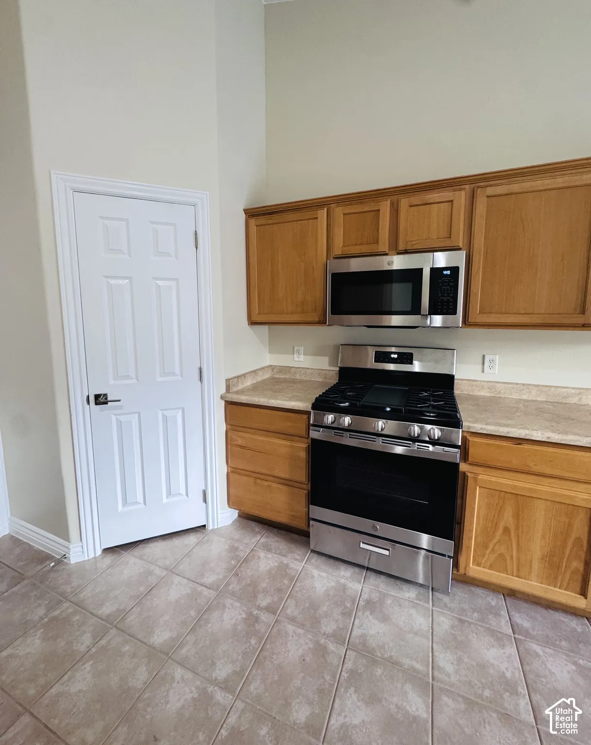 Kitchen featuring stained wood cabinetry, stone-finish countertops, tile flooring, and stainless steel appliances