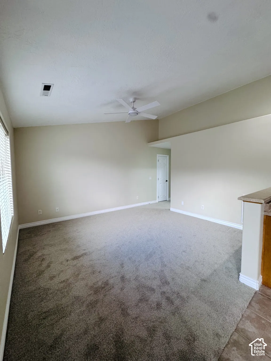 Room featuring vaulted ceilings, neutral wall tones, wall-to-wall carpeting, and a ceiling fan