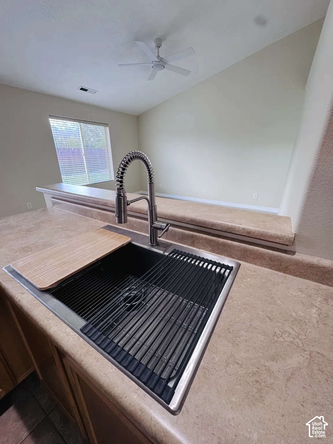 Kitchen island featuring solid surface countertops, a stainless steel undermount sink, a high-arc professional-style faucet, and an integrated roll-up sink rack