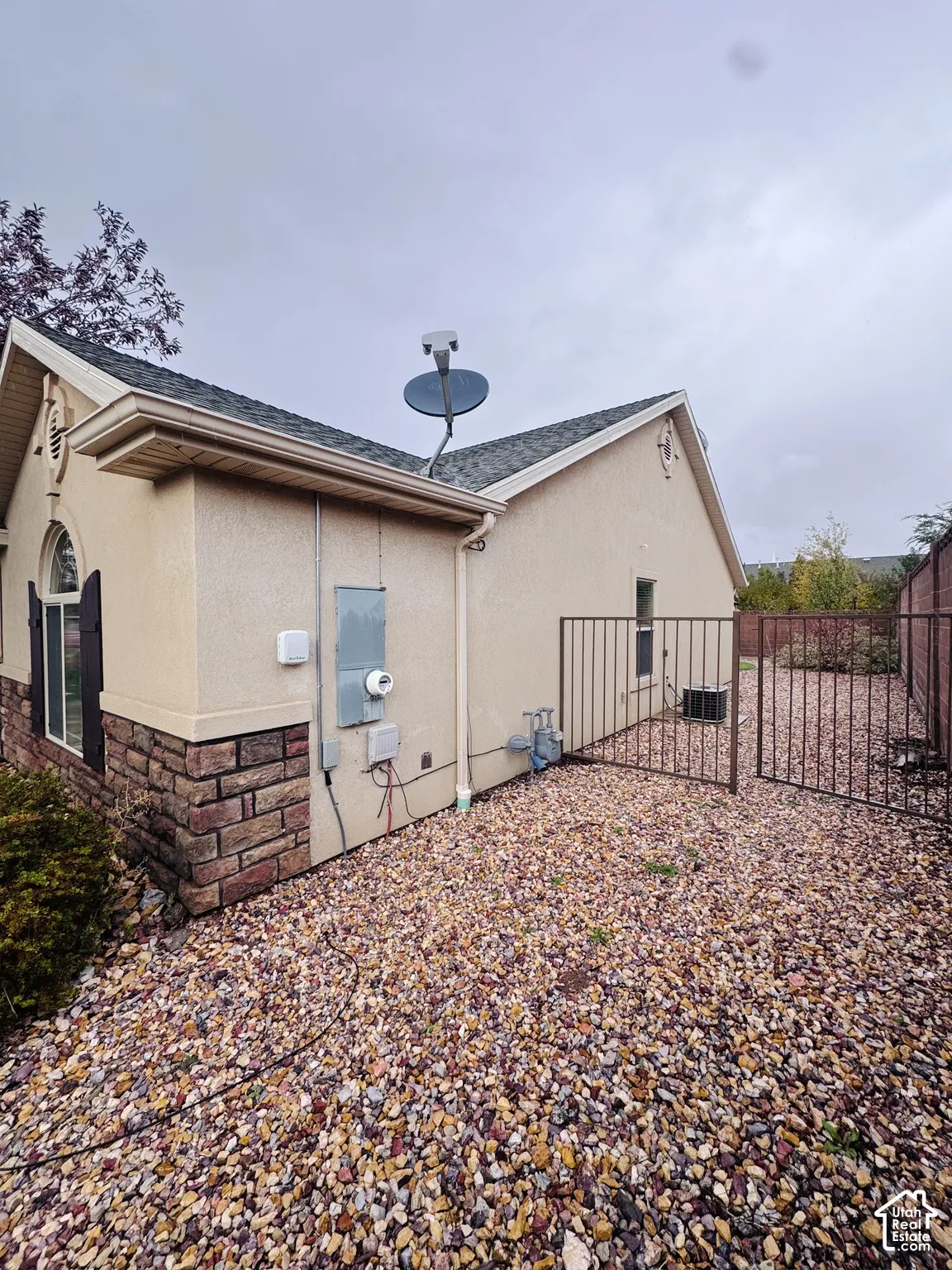 Stucco exterior featuring stone veneer accents, arched window detailing, and a metal security gate