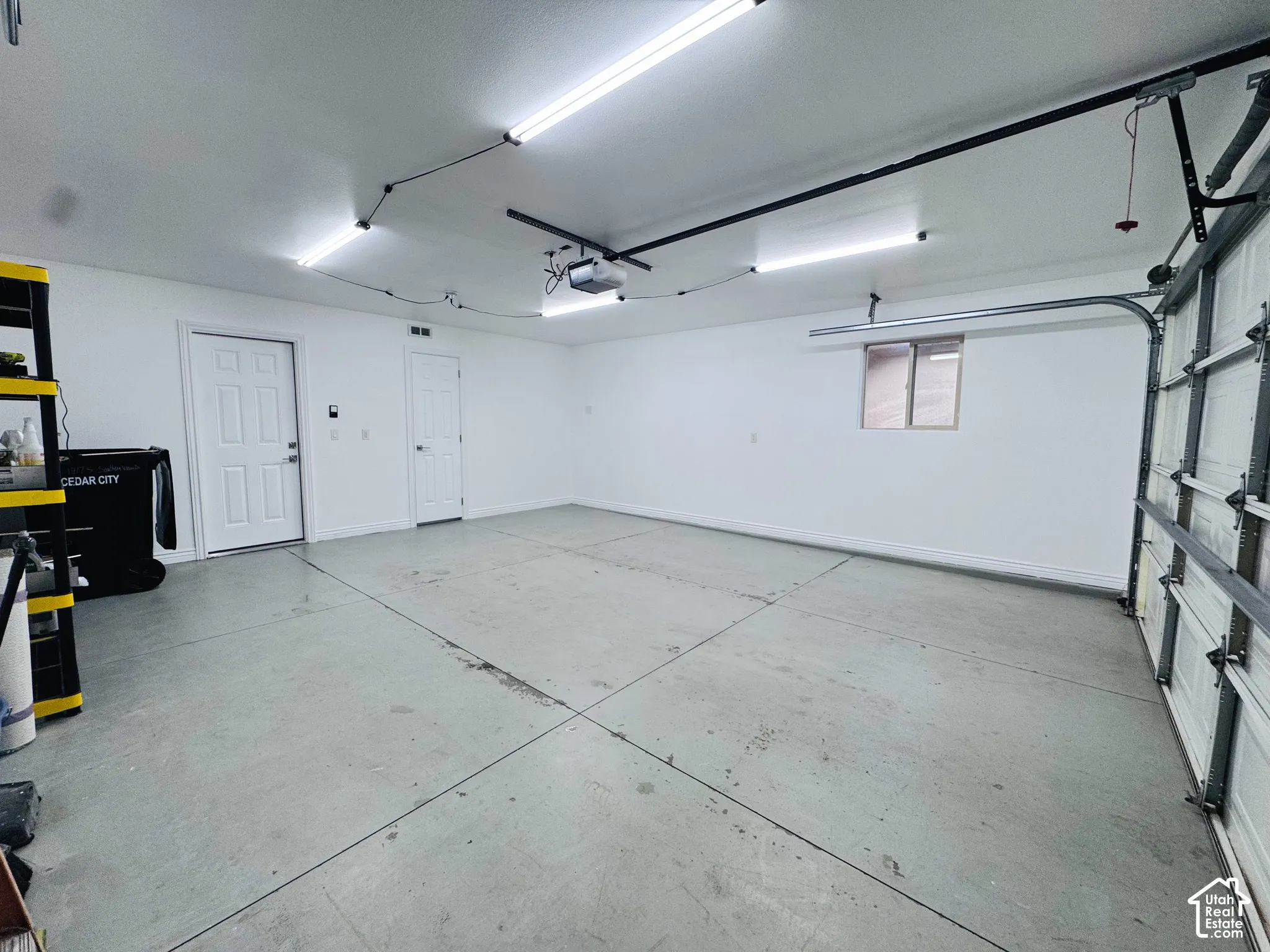 Multi-car garage featuring finished walls, overhead fluorescent lighting, a motorized door opener, and a single-pane window