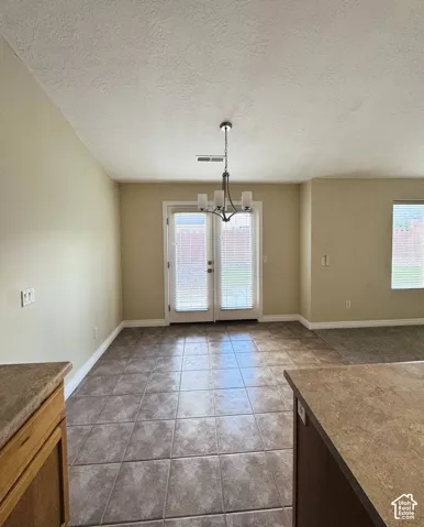 Ceramic tile flooring, glass-paned double doors, multi-arm metal chandelier, and vaulted ceiling