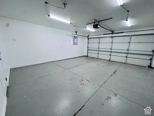Multi-car garage featuring a sectional overhead door, painted concrete flooring, linear lighting, and a window