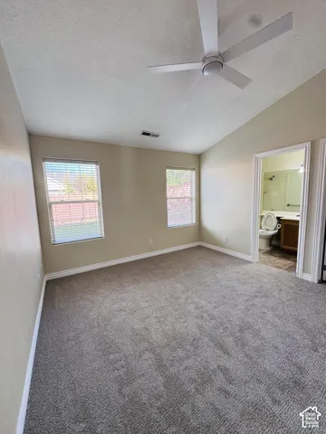Vaulted ceilings, neutral wall tones, carpeted flooring, two dual-pane windows, and a modern ceiling fan