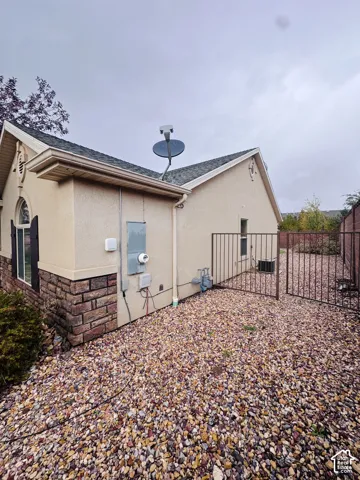 Stucco exterior featuring stone veneer accents, arched window detailing, and a metal security gate