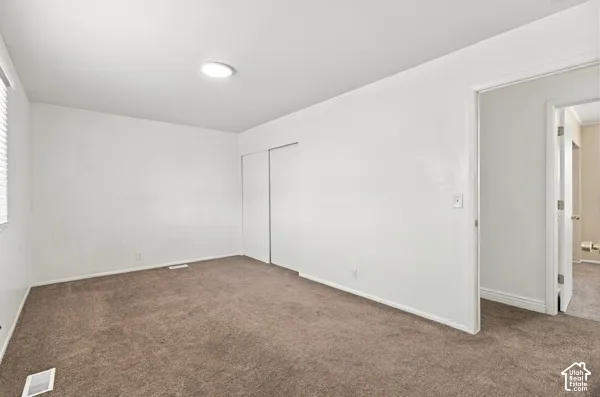 Neutral-toned wall-to-wall carpeting, flush-mount ceiling light fixture, and interior closet with sliding doors